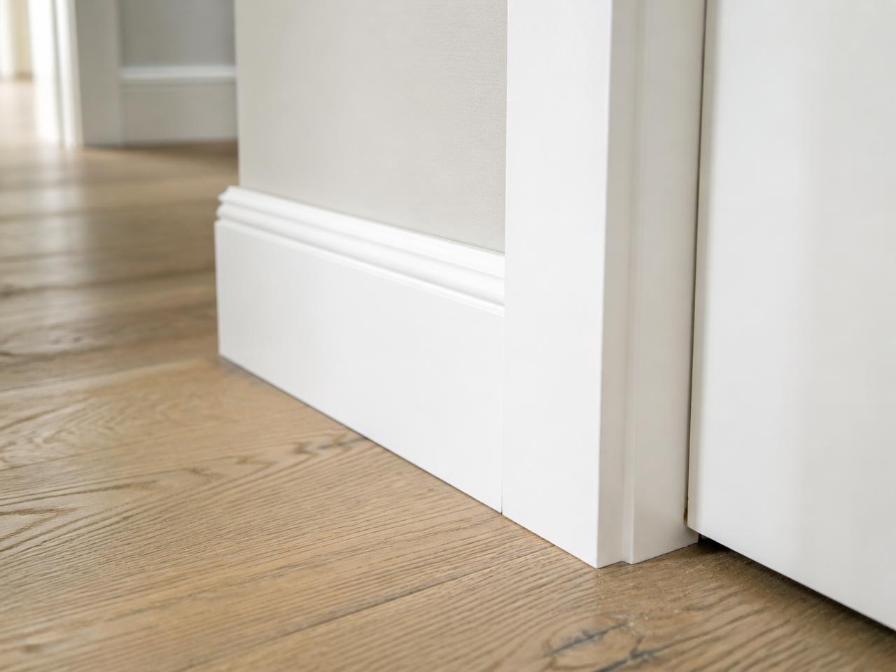 Close-up of finished baseboard and door casing meeting oak flooring